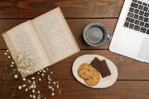 テーブルの上に置かれた英語の書籍とクッキーとコーヒー